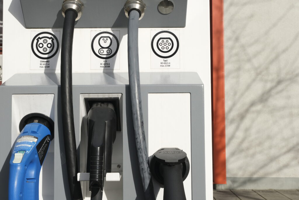 Elektro-Strom-Tankstelle im Abendlicht, drei verschiedene Anschlüsse, einer ladend.